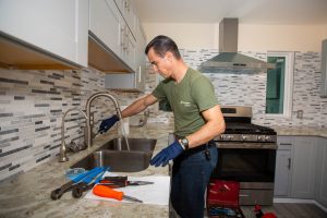 H-Town Plumbers plumber working on a kitchen sink faucet