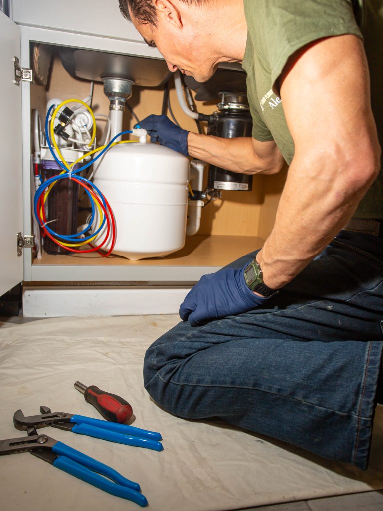H-Town Plumbers plumber working under a kitchen sink