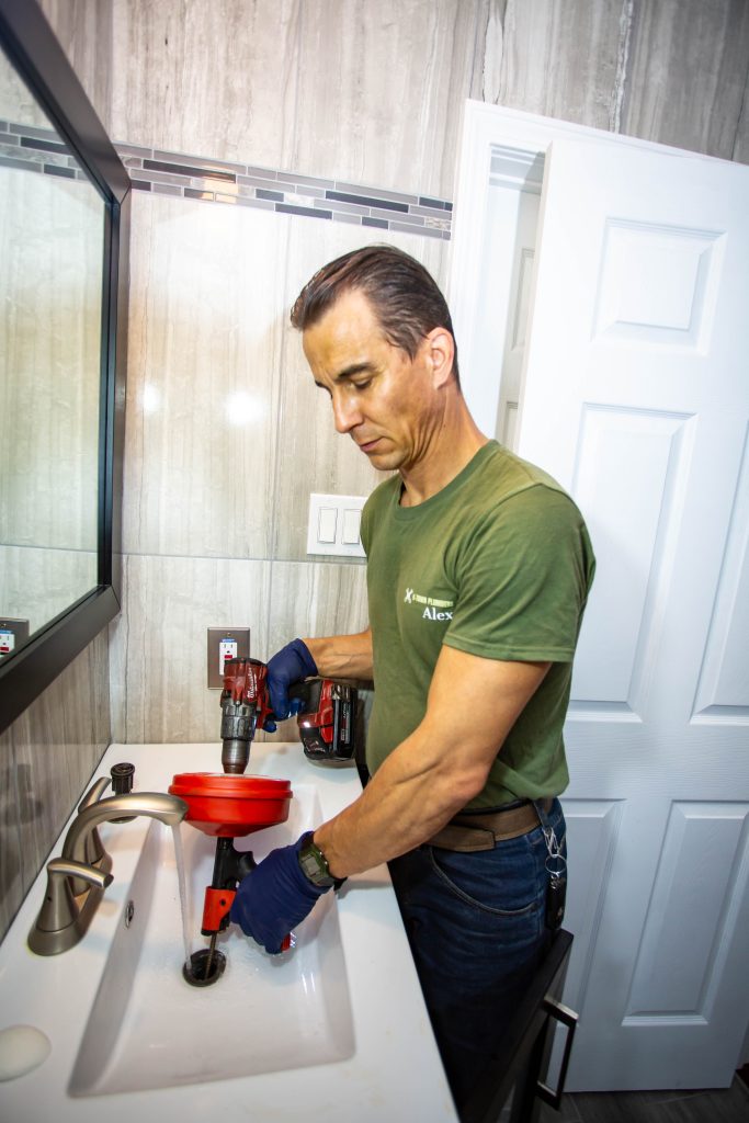 H-Town Plumbers plumber clearing a clogged bathroom sink drain