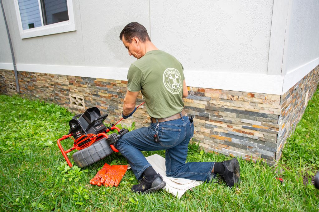 H-Town Plumbers plumber using a drain cleaning machine on an outdoor sewer cleanout
