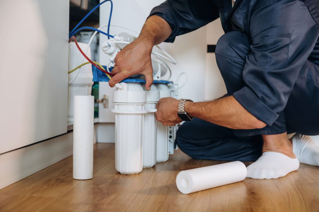 Plumber installing an under-sink water filtration system