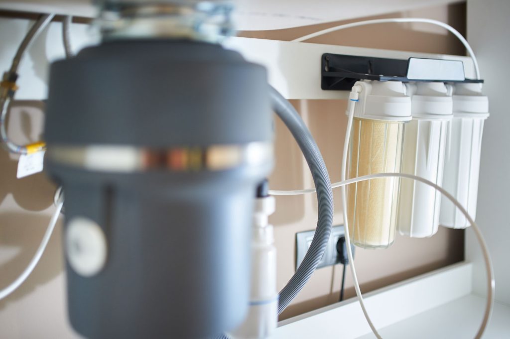 Under-sink reverse osmosis water filter next to a garbage disposal